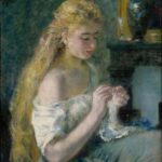 A young woman with long blonde hair, wearing an off-the-shoulder white dress, sits and knits in soft light. The background features dark tones, a vase, and a glass, creating a calm, intimate atmosphere.